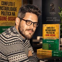 Ângelo Vasco, da University of Oxford, junto a exemplares do livro Conflito e Instabilidade Política na Guiné-Bissau, de Tamilton Teixeira, editado pela Nimba Edições